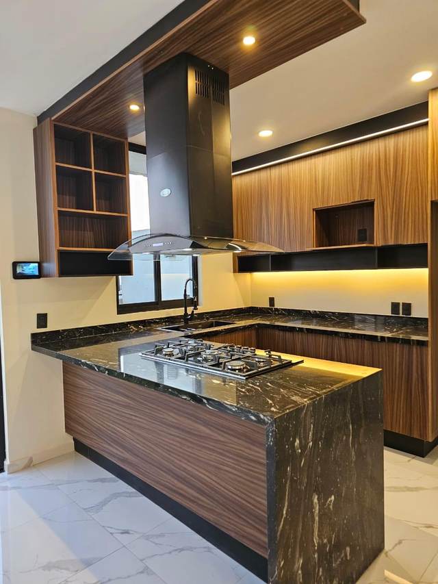 Isla de cocina con cubierta en piedra oscura y gabinetes de madera natural