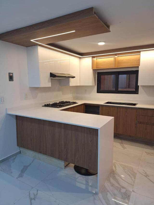 Cocina con península en madera y techo con iluminación integrada