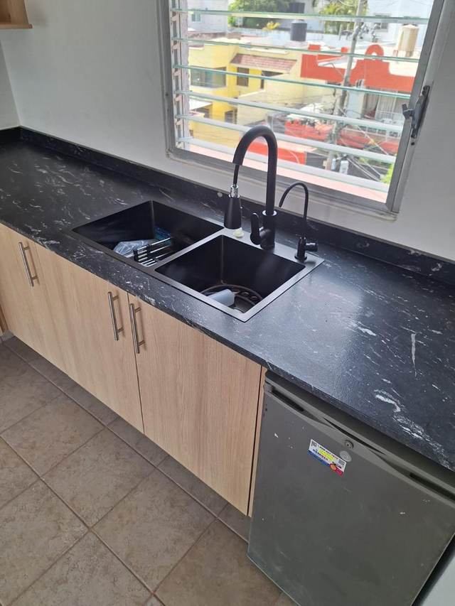 Lavabo doble en mármol negro con gabinete de madera y luz natural