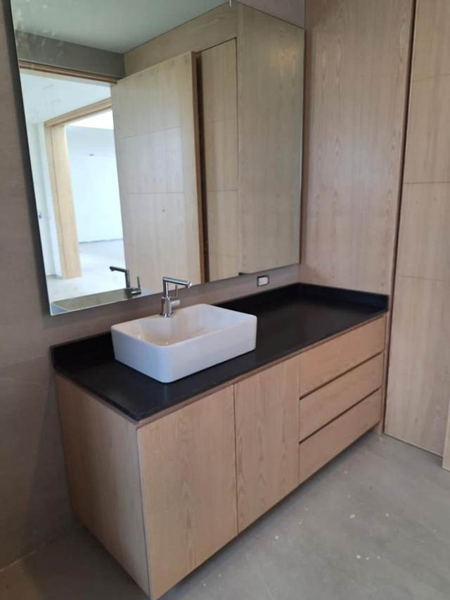 Lavabo ovalado sobre cubierta de mármol negro con gabinete de madera