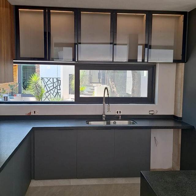 Cocina con cubierta en granito negro y gabinetes superiores de cristal