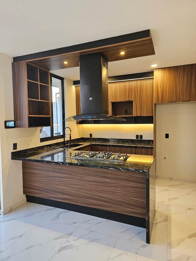 Cocina de concepto abierto con campana de cristal y cubierta en granito negro
